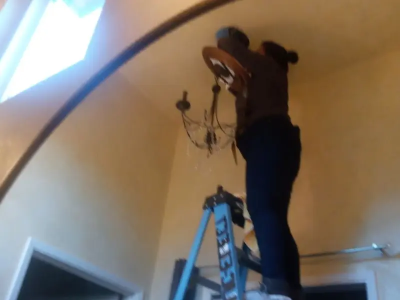 Electrician installing a chandelier in a Long Branch residence